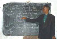 A male health professional giving a lecture stands in front of the blackboard.