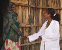 A health professional greets a woman outside her home.