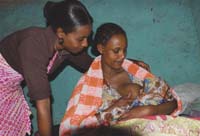 A healthcare worker counsels a mother on correct breastfeeding techniques whilst the mother is breastfeeding.