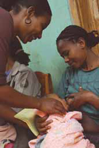 A health professional is showing anew mother how to improve her breastfeeding technique. A baby suckles on her mother's teat.