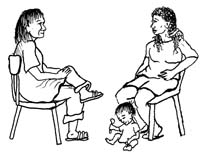 A health professional and pregnant woman sitting down at the first antenatal check-up. A baby sits playing by its mother's feet.