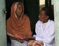 A health worker counsels a woman. They sit side by side and the health worker is holding the woman's hand.