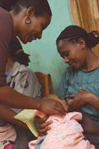 A health worker is showing anew mother how to improve her breastfeeding technique. A baby suckles on her mother's teat.